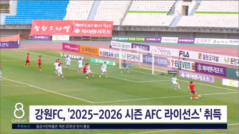 축구 경기장에서 강원FC와 상대팀 선수들이 경기를 펼치고 있으며, 하단에는 '강원FC, 2025-2026 시즌 AFC 라이선스 취득'이라는 뉴스 자막이 표시되어 있다.