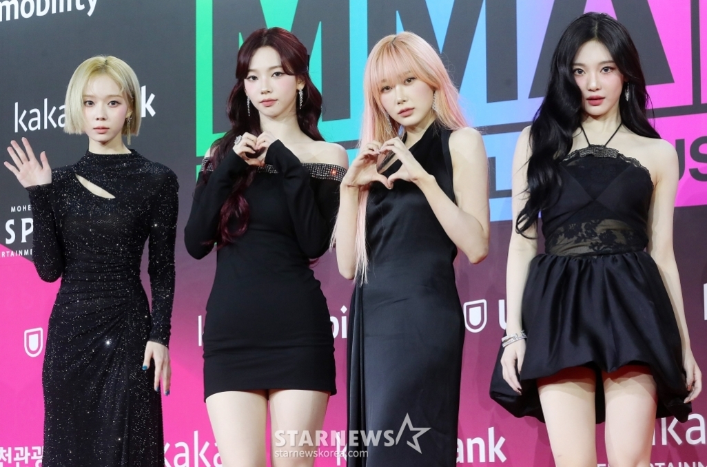 레드카펫 행사에서 블랙 드레스를 입은 네 명의 여성들이 포즈를 취하고 있다.