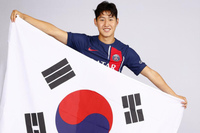 파리 생제르맹 축구 유니폼을 입은 남성이 태극기를 들고 미소 짓고 있다.