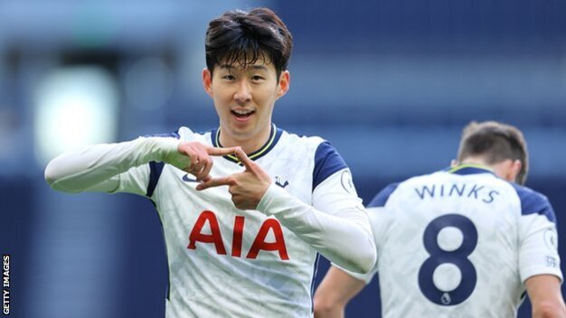 축구 경기장에서 토트넘 홋스퍼 유니폼을 입은 선수가 골 세리머니로 손가락으로 알파벳 모양을 만들고 있다. 뒤에는 등번호 8번 선수도 보인다.
