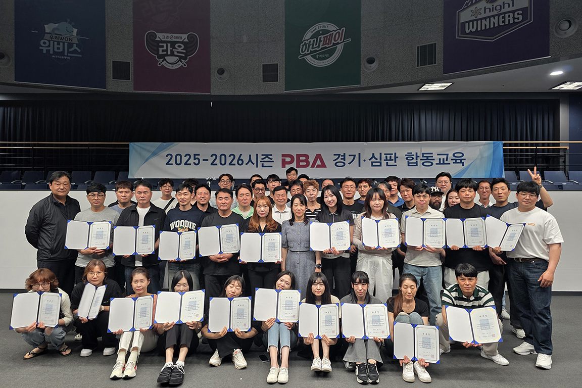 단체로 모인 사람들이 '2025-2026시즌 PBA 경기·심판 합동교육'이라는 현수막 앞에서 수료증을 들고 기념사진을 찍고 있다.