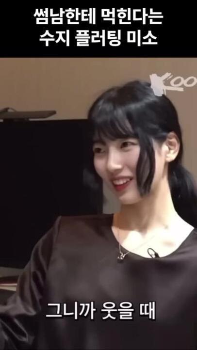 검은 머리의 여성이 미소를 지으며 옆을 바라보고 있다. 이미지 상단과 하단에 한글 자막이 있다.