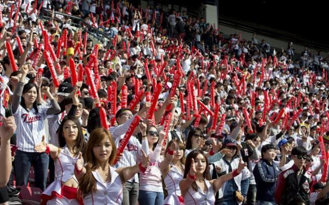 야구 경기장에서 많은 관중들이 빨간 응원 막대를 들고 열정적으로 응원하고 있다.