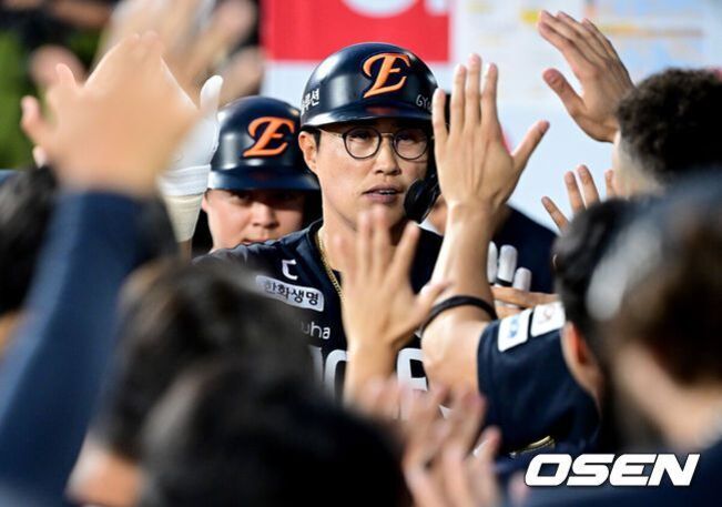 야구 헬멧을 쓴 한화 이글스 선수와 팀원들이 하이파이브를 나누는 모습
