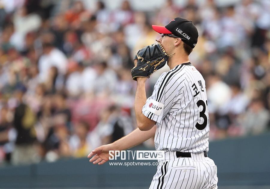 야구 경기장에서 LG 트윈스 유니폼을 입은 투수가 마운드 위에서 글러브로 입을 가리고 있다. 배경에는 관중들이 앉아 있다.