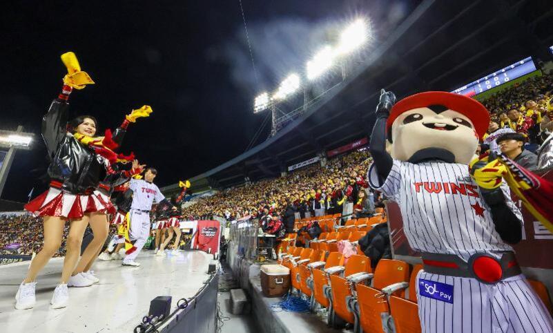 야구 경기장에서 치어리더와 마스코트가 관중을 향해 응원하고 있는 모습