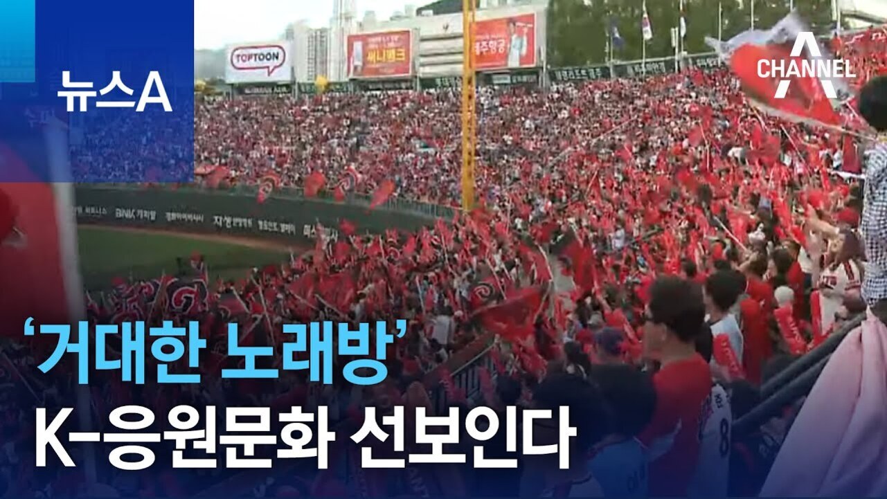 야구 경기장에서 많은 관중들이 빨간색 응원 도구를 들고 열렬히 응원하는 모습과 '거대한 노래방' K-응원문화 선보인다라는 뉴스 자막이 보인다.