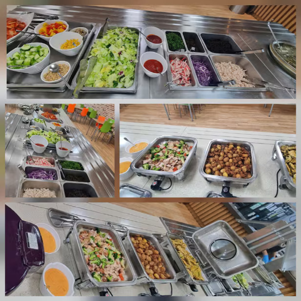 여러 종류의 샐러드 재료와 소스, 다양한 야채, 삶은 달걀, 닭고기 등이 놓인 뷔페식 식사대. 따뜻한 음식과 샐러드를 선택할 수 있는 셀프서비스 코너가 보인다.